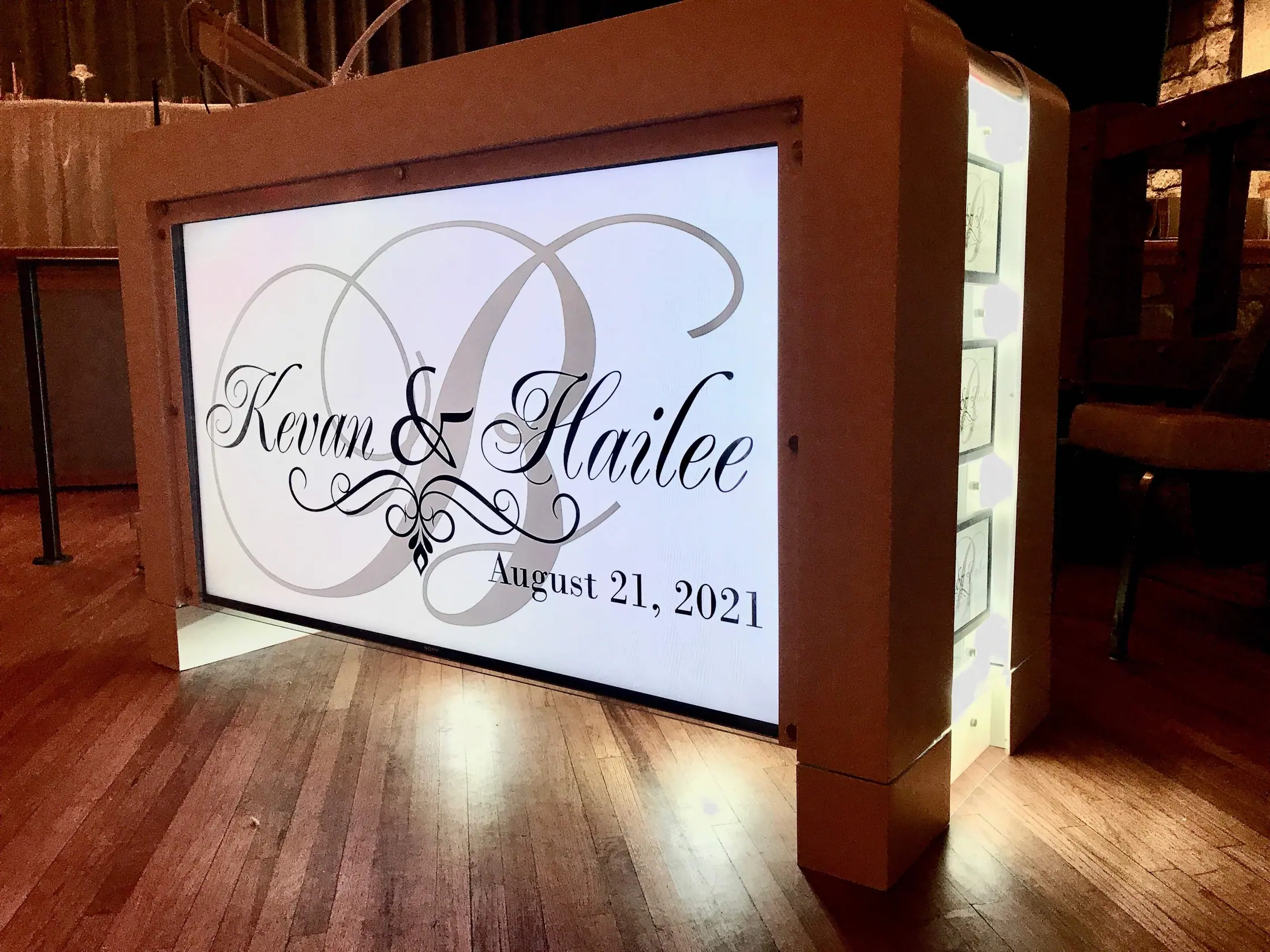 Video DJ booth glowing with a custom wedding monogram on a wooden dance floor